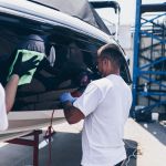 Boat maintenance - Man with orbital polisher polishing boat in marina. Selective focus.